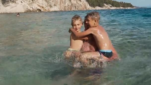 Счастливый отец с двумя детьми прыгает в море весело. Счастливая семья в отпуске. Далмация. Хорватия — стоковое видео