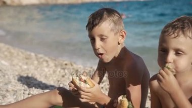 Adriyatik Denizi kıyısında iki güzel adam lezzetli hamburger yemek. Deniz, güneş, dinlenme, tatil
