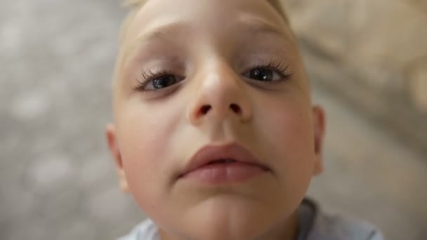 Um garotinho com belos olhos escuros e pálpebras grandes beija o objetivo das câmeras. Lindo menino. — Vídeo de Stock