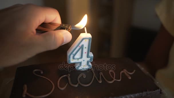 Pastel de chocolate en el cumpleaños de un niño pequeño. El cumpleaños de los niños, encendemos una vela en un pastel. Infancia a medida, un aniversario, felicidad. Cuatro años. — Vídeos de Stock