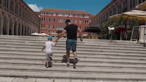 The father and his son have fun climbing up the stairs on Splits square. Croatia — Stock Video