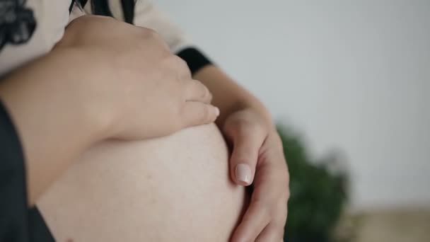 Eine Schwangere berührt ihren Bauch sanft mit den Händen. Warten auf das Kind — Stockvideo