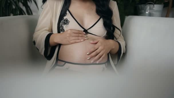 Jovem grávida segura os braços em seu estômago. Gravidez por 8 meses — Vídeo de Stock