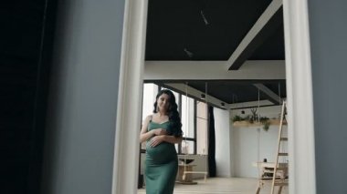 Akşam yeşil elbiseli güzel hamile kız Aynaya bakar
