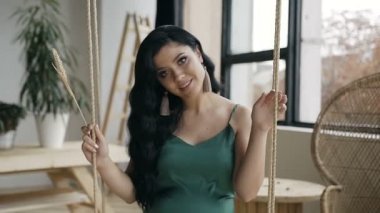 Tahta salıncakta sallanan ve kameraya bakarak uzun saçlı genç güzel pregancy kız