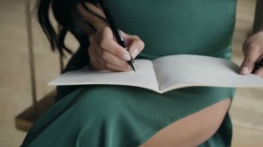 Genç bir kadın bir defter Siyah kalemle bir not yazıyor