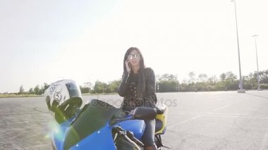 Bir genç Motorcu kız siyah saçlı deri ceket ve güneş gözlüğü ile onun motosiklet üzerinde oturur ve Evet eğlenceli