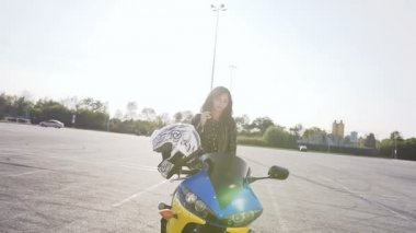 Genç kadın motorcu günbatımında, oturur onun motosiklet ve giyen güneş gözlüğü