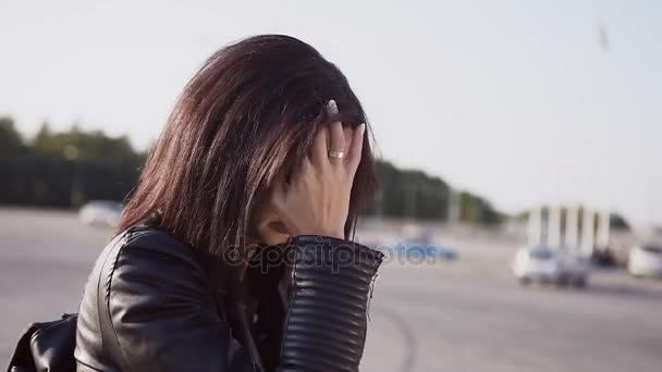 Uma linda jovem conserta o cabelo e usa óculos de sol. O motociclista segura o telefone na mão — Vídeo de Stock