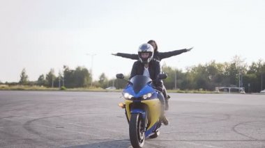 İyi eğlenceler bir genç adam ve genç bir kadın şık giysiler giymiş bir motosiklet binme. Onların motosiklet bisikletçileri genç Çift