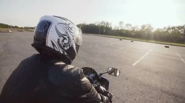 Bir kask içinde genç bir bisikletçinin motosikletine biniyor. Yakın çekim