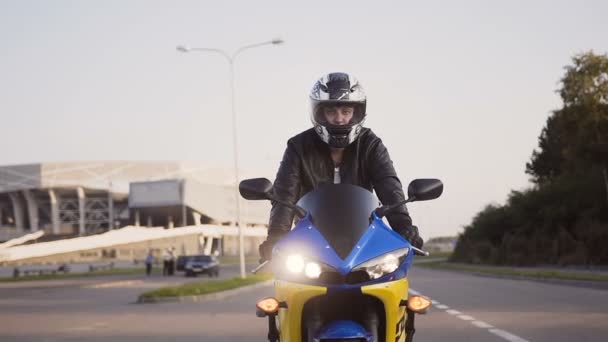 Motocyklista jede město na motorce žluto modré přilby a koženou bundu