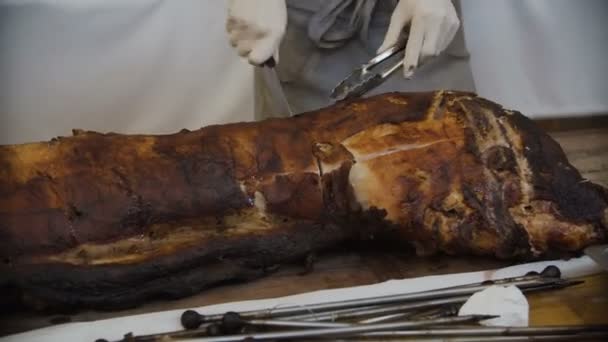 The cook sliced roasted meat with a knife. Grilled pig on the fire — Stock Video