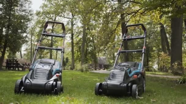 Dos cortadoras de césped están en el parque en la hierba — Vídeos de Stock