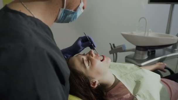 Dientes sanos en la chica de los pacientes. El dentista examina los dientes de los pacientes a través del espejo — Vídeos de Stock