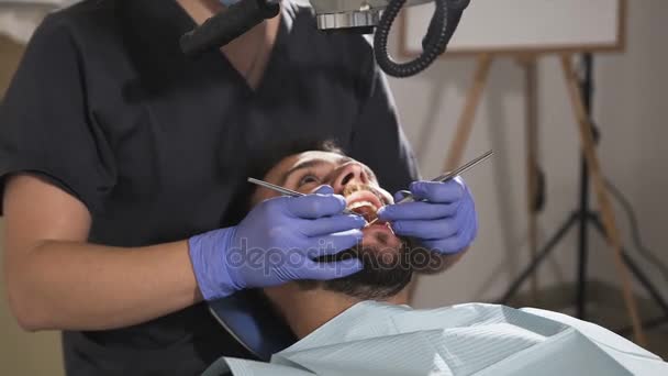 Tandläkaren undersöker patienter tänderna med hjälp av en spegel. Dentala instrument — Stockvideo
