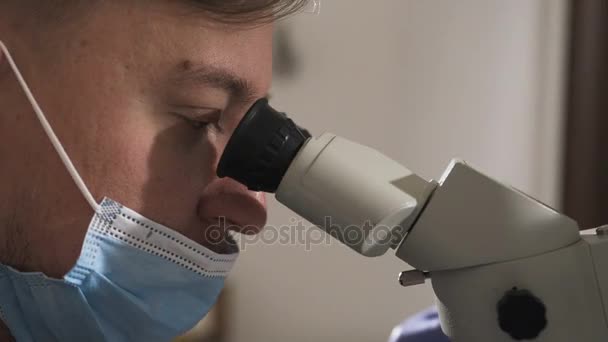 Dentista que utiliza el microscopio dental en el consultorio dental moderno para la operación de una mujer paciente odontología. Odontólogo masculino con herramientas dentales en clínica — Vídeos de Stock