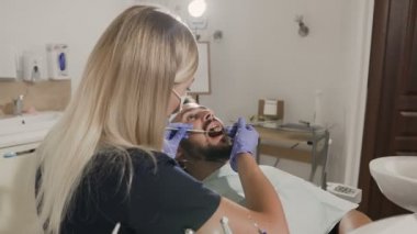 Bir kadın dişçi diş hastasını davranır.