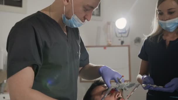 Zubař a jeho asistent použít tvář luk při léčbě pacientů zuby. Umístění horní čelisti oproti základu lebky — Stock video