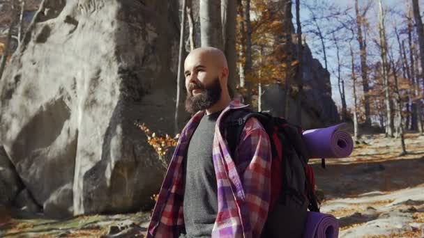髭のハンサムな若い男が入って暖かい秋の日。観光客は、秋の季節に森の中で旅しました。山の岩 — ストック動画