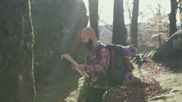 Elegante hombre hipster viajero con mochila sosteniendo mapa y explorando en la cima de las montañas concepto de viaje wanderlust — Vídeos de Stock