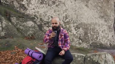 Bir kaya üzerinde dinlenmek için turist gitti yüksek bir kayalığın aldı sıcak fincan çay sırt çantası üzerinden çay içmek ve sıcak sonbahar hava keyfini çıkarın