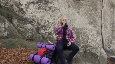 Bir kaya üzerinde dinlenmek için turist gitti yüksek bir kayalığın aldı sıcak fincan çay sırt çantası üzerinden çay içmek ve sıcak sonbahar hava keyfini çıkarın