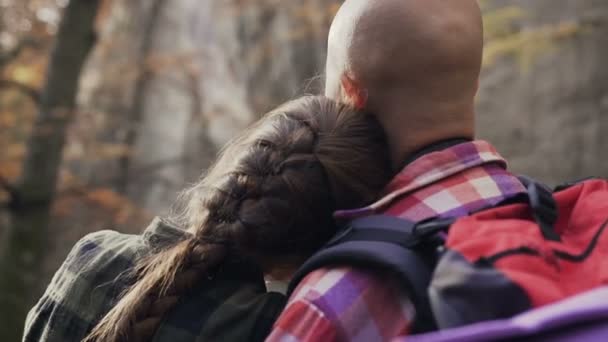 Close-up Una chica con el pelo largo trenzado en una trenza abrazada a su novio. Turistas en el bosque — Vídeos de Stock