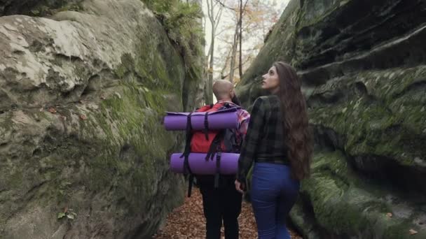 Close-up. Man en vrouw met een rugzak wandelen langs het pad van een voetpad tussen de rotsen tijdens het zonnige zonnige herfstdag — Stockvideo