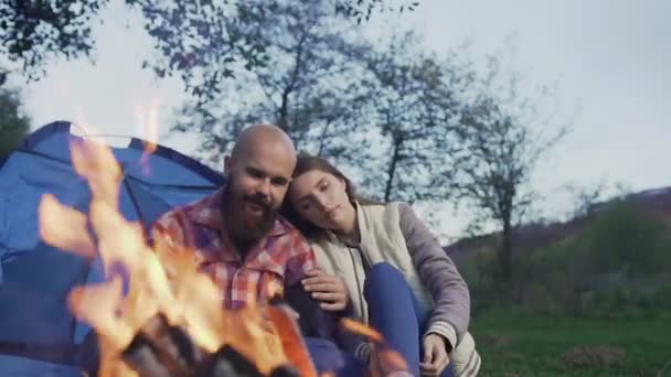 Um jovem casal de hippesters se senta no fogo hte em uma cidade tenda — Vídeo de Stock