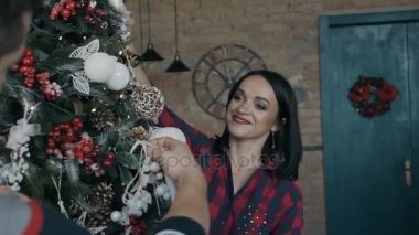 Portre. Güzel bir genç kadın kocasıyla neşeyle bir Noel ağacı süsle. Mutlu bir aile. Noel akşam