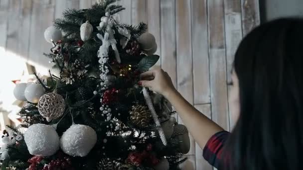 Крупный план красивой молодой девушки, украшающей декоративную елку на Рождество. Декорации рождественских елок — стоковое видео