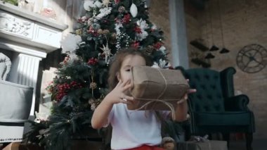 Noel ağacı yakınındaki bir şömineli oturma odasında oturma ve bir kutu hangi tutarak uzun saçlı güzel bir kız bir hediye