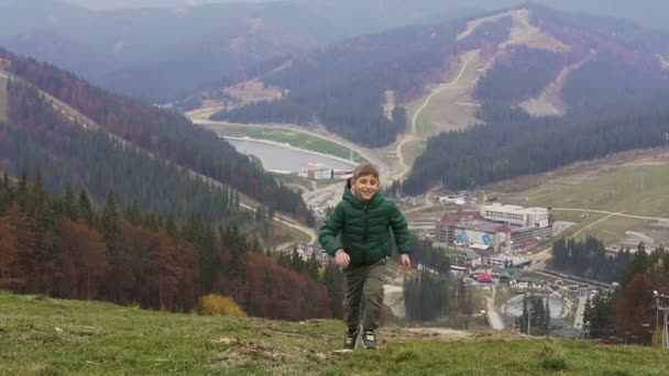 Um lindo menino correndo divertido no topo da montanha e sorri para a câmera. O conceito de outono. Bukovel. — Vídeo de Stock