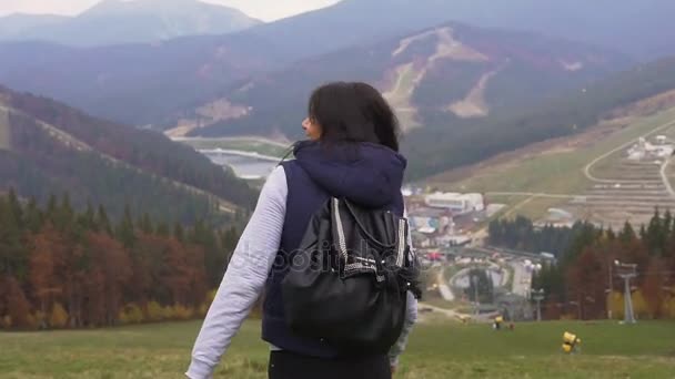 Ung vacker flicka stiger ned från berget på en bakgrund av skog under hösten. Lycklig kvinna i bergen på solig höstdag. Bukovel — Stockvideo