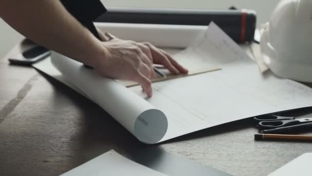 Close-up de architect is bezig aan een nieuw project. De man - de architect schildert een plan, ontwerp, grafische en geometrische vormen met een potlood op een groot vel papier op het Bureau — Stockvideo