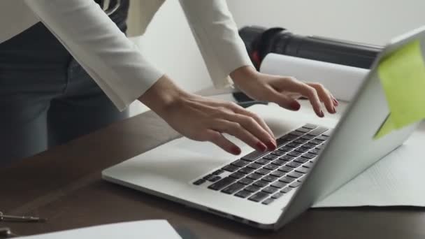 Närbild. Unga kvinnliga arkitekt arbetar med en laptop och ritningar som ligger på skrivbordet på kontoret — Stockvideo