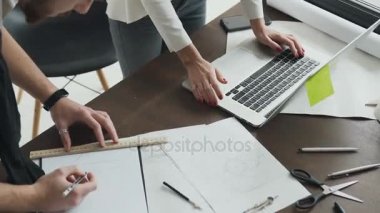 Yakın çekim. Ofiste iki mimar ekip çalışması. Tasarım planlama projede değiştirir. Bir proje bir taslak üzerinde çizmek ve dizüstü bilgisayarınıza aktarın