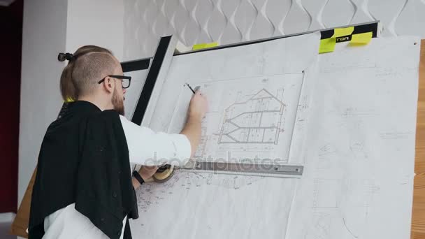 Een close-up van een mannelijke architect die een baard en bril heeft werkt aan een project van een residentieel gebouw — Stockvideo