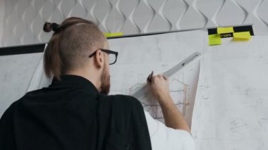 Büyük bir plan. Çizimler ve yeni projeler çizimler üzerinde çalışan bir mimar içeren bir tablo