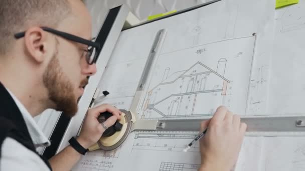 Un primer plano de un arquitecto que tiene barba y gafas está trabajando en un proyecto de un edificio residencial — Vídeos de Stock