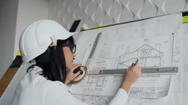 Primer plano. Joven arquitecta que trabaja en el dispositivo de dibujo un proyecto de anteproyecto de nuevo edificio residencial. Concepto de trabajo sobre dibujos técnicos — Vídeo de stock