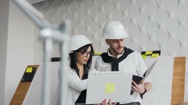 Yakın çekim. Güzel genç tasarımcılar klasör tartışırken fikirler çizim ve ofiste çalışırken gülümseyen ile bir dizüstü bilgisayar ve kağıt kullanıyorsanız