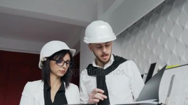 Beyaz kask inşaat alanı üzerinde çalışmak ve klasörlerine belgelerini sağlanan bilgileri tartışmak iki genç mimarlar