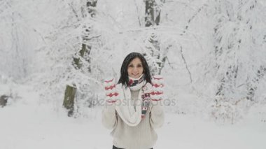 Karla kaplı orman ve dokuma mittens onun elleri Merhaba sallayarak koyu saç yün kazak ve sıcak bir eşarp ile gülümseyen genç bir kadın olduğunu