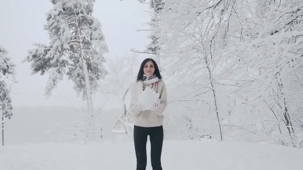 素敵な笑顔を持つフォレストの空気で雪を投げ休暇にブルネットの女性。かわいい女の子は、白いマフラーとニットのミトン、スタイリッシュなセーターと赤を着用します。天気の良い日と降雪. — ストック動画