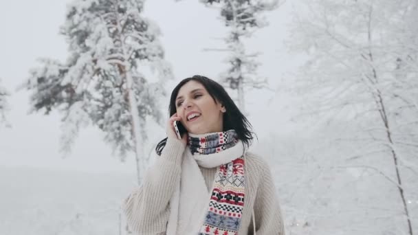 Азиатская молодая женщина, одетая в теплый свитер и теплый шарф, разговаривает по телефону на улице и отворачивается — стоковое видео