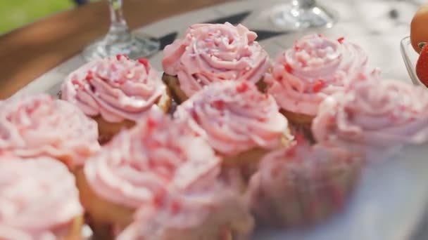 Detail sladkého pečiva v koších s růžovým chutné krémem na dezertní talířek, který stojí na stole — Stock video