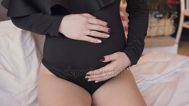 Close-up das mãos de uma mulher grávida que acaricia o abdômen com as mãos. Concepção da gravidez — Vídeo de Stock