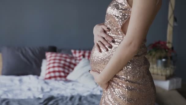 Закрывай. Беременная женщина в великолепном платье держит живот в руках и смотрит вдаль — стоковое видео